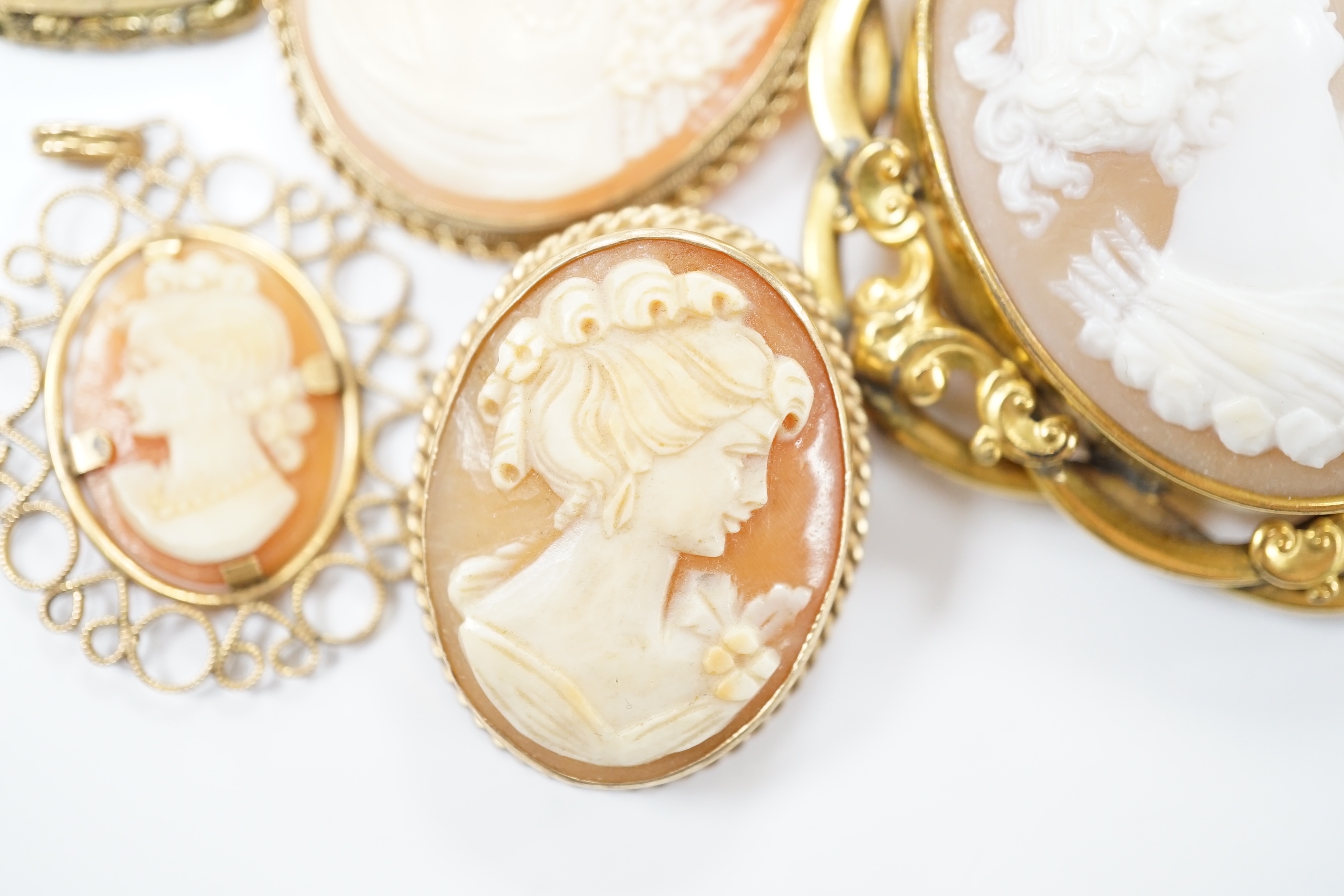 Two modern 9ct gold mounted oval cameo shell pendant brooches, largest 42cm and two other mounted oval cameo shell pendant or brooches and a mourning brooch (a,f,).